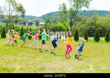 Kids train on the lawn. Children follow to each others and run together holding hands Stock Photo