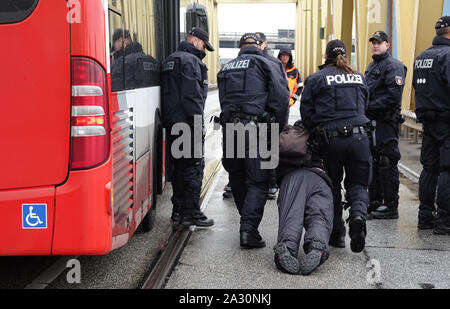 Hamburg, Germany. 04th Oct, 2019. A climate activist is pulled across the road by police during a blockade of the Kattwyk bridge in the harbour. Around 120 climate activists occupied the Kattwyk Bridge in the Port of Hamburg and paralyzed traffic for several hours. Under the motto 'DeCOALonize Europe', they demanded the immediate withdrawal from lignite and hard coal as well as the closure of all coal-fired power plants in Hamburg and the coal port in Hamburg. (to dpa 'Protest against coal-fired power plant Moorburg - activists occupy bridge') Credit: Magdalena Tröndle/dpa/Alamy Live News Stock Photo