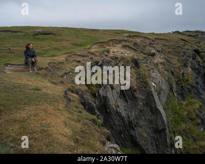 Woman sitting on cliff, Achill Island, County Mayo, Ireland Stock Photo