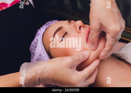 cosmetologist makes a buccal massage of the patient's facial muscles. Stock Photo