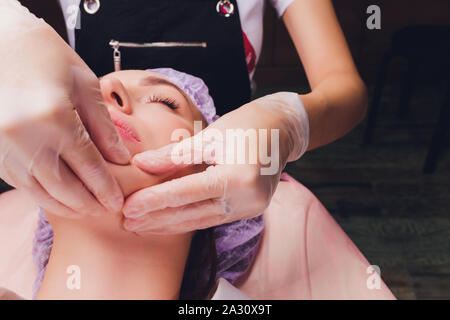 cosmetologist makes a buccal massage of the patient's facial muscles. Stock Photo