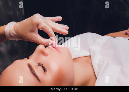 cosmetologist makes a buccal massage of the patient's facial muscles. Stock Photo