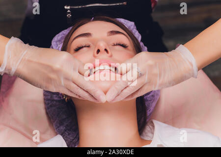 cosmetologist makes a buccal massage of the patient's facial muscles. Stock Photo