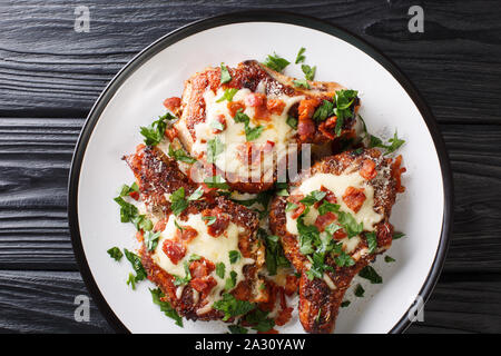 Tasty pork chops with melted parmesan and bacon closeup on a plate on the table. Horizontal top view from above Stock Photo
