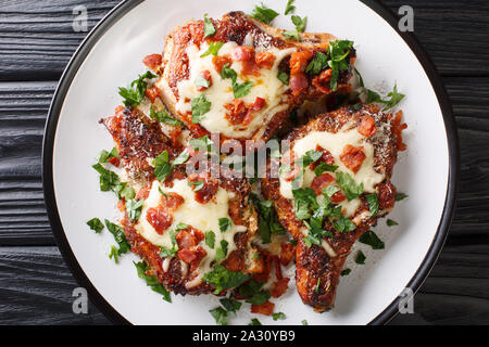Cooked juicy pork chops with parmesan and bacon closeup on a plate on the table. Horizontal top view from above Stock Photo