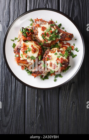 Grilled pork chops with parmesan and bacon closeup on a plate on the table. Vertical top view from above Stock Photo