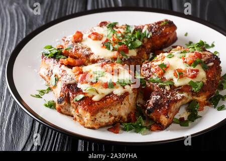 Tasty pork chops with melted parmesan and bacon closeup on a plate on the table. horizontal Stock Photo
