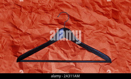 Black Friday sale concept with fashion clothes hanger on red coral color wrapping paper background. Shopping. Outfit. Flat lay, top view. Stock Photo