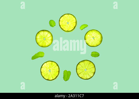 Trendy pattern with lime slices and green mint leaves in mint color on bright neo mint background. Minimal summer concept of peppermint. Flat lay, top Stock Photo