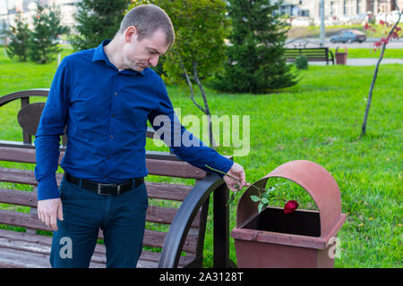 A sad man did not wait for his beloved and in desperation threw the rose into the trash Stock Photo