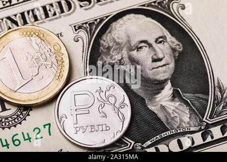 Coin 1 euro and 1 Russian ruble against the background of a dollar bill. On the coin is the inscription in Russian letters ruble Stock Photo