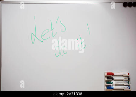 White board with colored markers and the words Let's do it written on Stock Photo