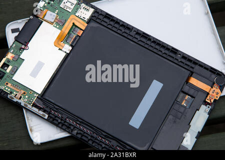 Dismantled broken electronic tablet device on a wooden bench Stock Photo