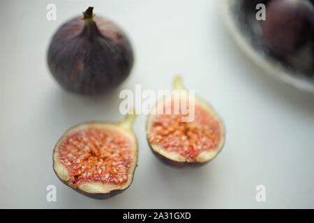 One whole fig and the second cut in half on a white table. Selective focus. Stock Photo