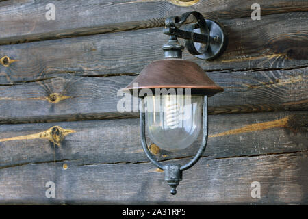 Horizontal shot of a street lamp hanging on the wall from old weathered and grayed logs on a Lithuanian farm. Stock Photo