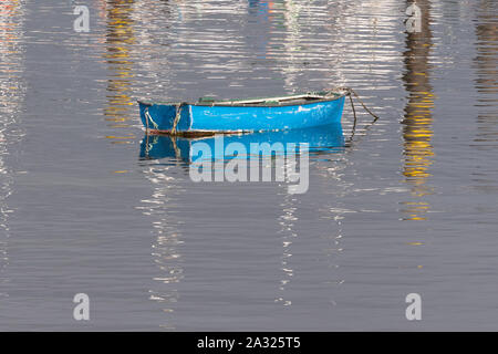 empty blue rowing boat with reflections