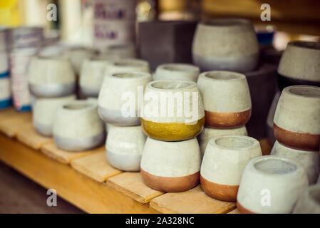Assortment of gray color cement flower pots with colored part selling in gardening store. Pile of pots made from clay and cement. Modern design and in Stock Photo