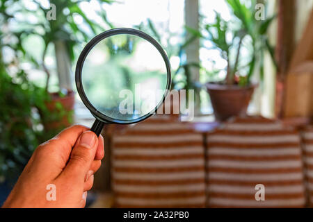 Searching for signs of moisture inside a family home, using a magnifying glass in a point of view (POV) perspective, with blurry background and copy-space. Stock Photo