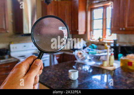 Searching inside the family kitchen using a magnifying glass in first person view (FPV), during a home environmental quality survey with room for text. Stock Photo