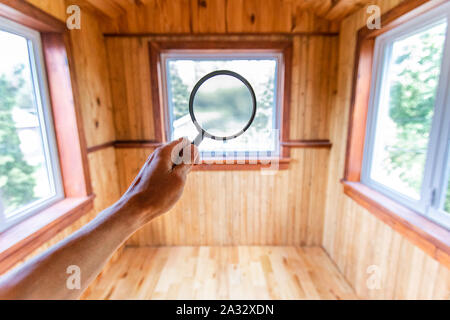 Searching for home defects & imperfections during indoor environmental quality assessment, using a magnifying glass in first person perspective with copy space. Stock Photo