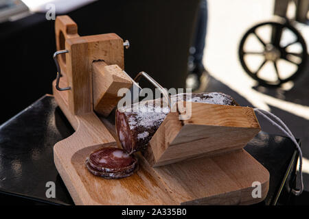 A traditional wooden salami slicer is seen close up on a market stall  during an agricultural and farming fair. Rustic butcher's tool for cutting  cured meats Stock Photo - Alamy