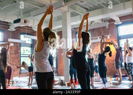 A wide angle view inside a gymnasium during a session honoring traditional 108 salutations to the sun (surya namaskar). Spiritual poses for health & wellness. Stock Photo