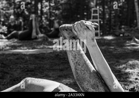 A close up and monochrome view on the dirty, mud splattered leg and arm of a person practicing yoga postures in woodland during retreat with room for copy. Stock Photo