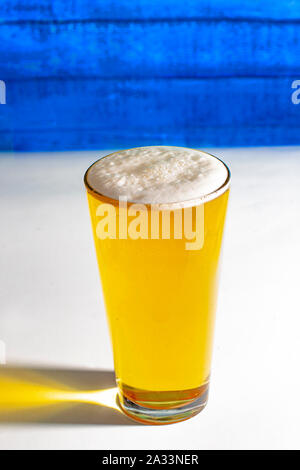 Light Pint Beer on a white table with a wooden wall. Stock Photo