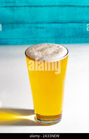 Light Pint Beer on a white table with a green wooden wall. Stock Photo