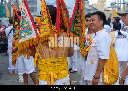A procession during the Vegetarian Festival in Phuket Town, Thailand with a participant displaying sacred flags attached to his back Stock Photo