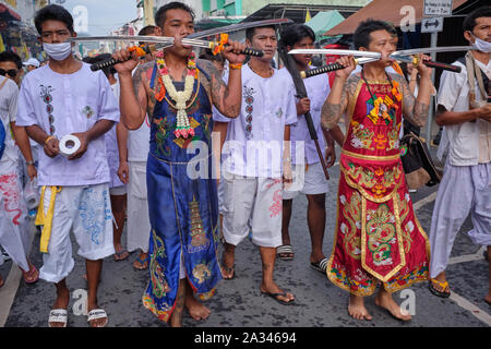 A procession during the Vegetarian Festival (Nine Emperor Gods Festival) in Phuket Town, Thailand, participants displaying cheeks pierced by swords Stock Photo