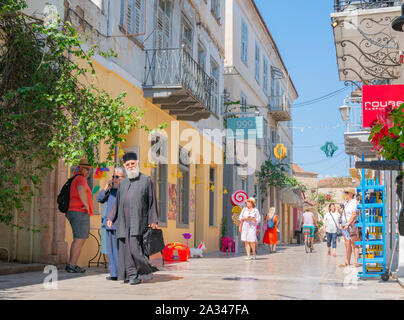 NAFPLIO GREECE - JULY 18 2019; Greek village of Nafplio street scene with Orthodox priest locals and tourists walking towards Stock Photo