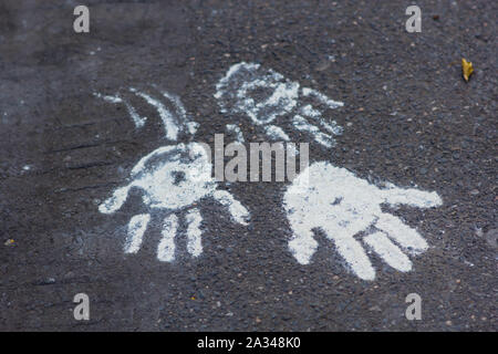 white clay palm prints on black asphalt Stock Photo