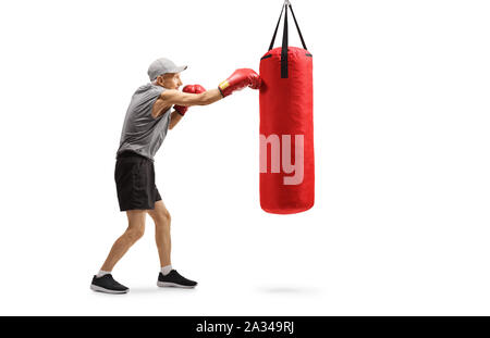 Full length profile shot of an elderly man with boxing gloves punching a boxing bag isolated on white background Stock Photo