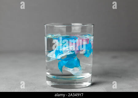 Microplastic. Water pollution by small particles of plastic. Glass of water with plastic. Stock Photo