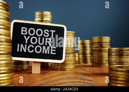 Boost Your Income concept. Stacks of coins and wooden plate. Stock Photo