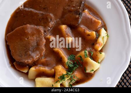 Croatian traditional cuisine, Pasticada With Gnocchi - Dalmatian Pot Roast or beef/ Croatian dish - Pasticada with gnocchi, beef stew in a sauce Stock Photo