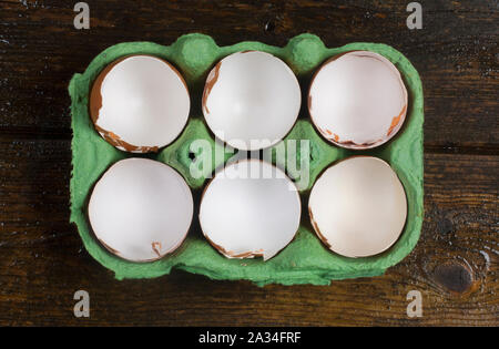 Studio shot of cracked, empty chicken egg shells in an egg box on a dark wooden background - John Gollop Stock Photo