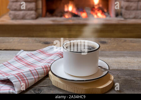 Cozy scene before fireplace with a cup of tea, in country house, winter vacation. Stock Photo