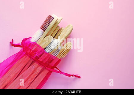 Bamboo toothbrushes  in crimson pouch that is reusable on trendy pink background. Eco-friendly products. Eco, zero waste and health concepts. Flat lay Stock Photo