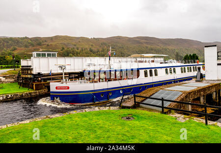 A boat passing through the opend swing bridge and entering the Caledonian Canal from Loch Oich near Aberchalder, Scotland Stock Photo