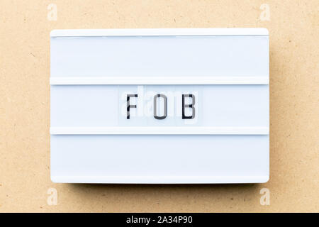 White lightbox with word FOB (Abbreviation of free on board) on wood background Stock Photo