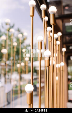 White round lamps on high metal stands of golden color. Beautiful festive illumination. Details of a modern wedding Stock Photo