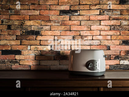 Toaster on wooden cupboard in kitchen room with vintage brick wall background Stock Photo