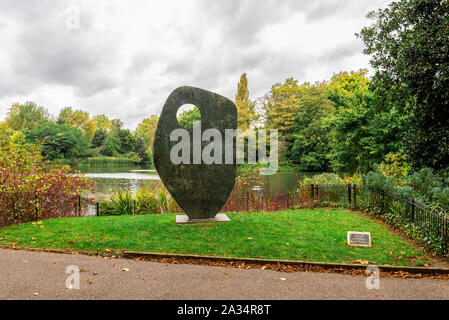 A Single Form statue in front of a boating lake in Battersea Park, London, United Kingdom Stock Photo