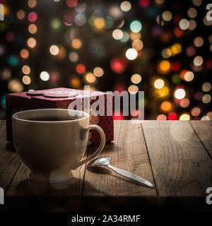 Hot coffee with gift box on wooden table in colorful bokeh background