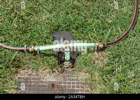 Water irrigation system in garden with two hosepipes attached to water supply Stock Photo
