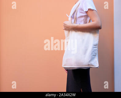 Blank white shopping canvas fabric cloth bag on female holding mockup and template isolated color background Stock Photo