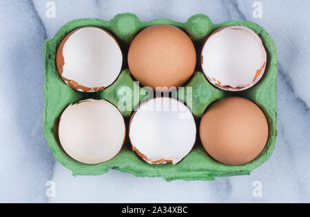 Studio shot of cracked, empty chicken egg shells in an egg box on a marble background - John Gollop Stock Photo