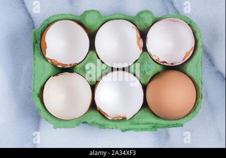 Studio shot of cracked, empty chicken egg shells in an egg box on a marble background - John Gollop Stock Photo